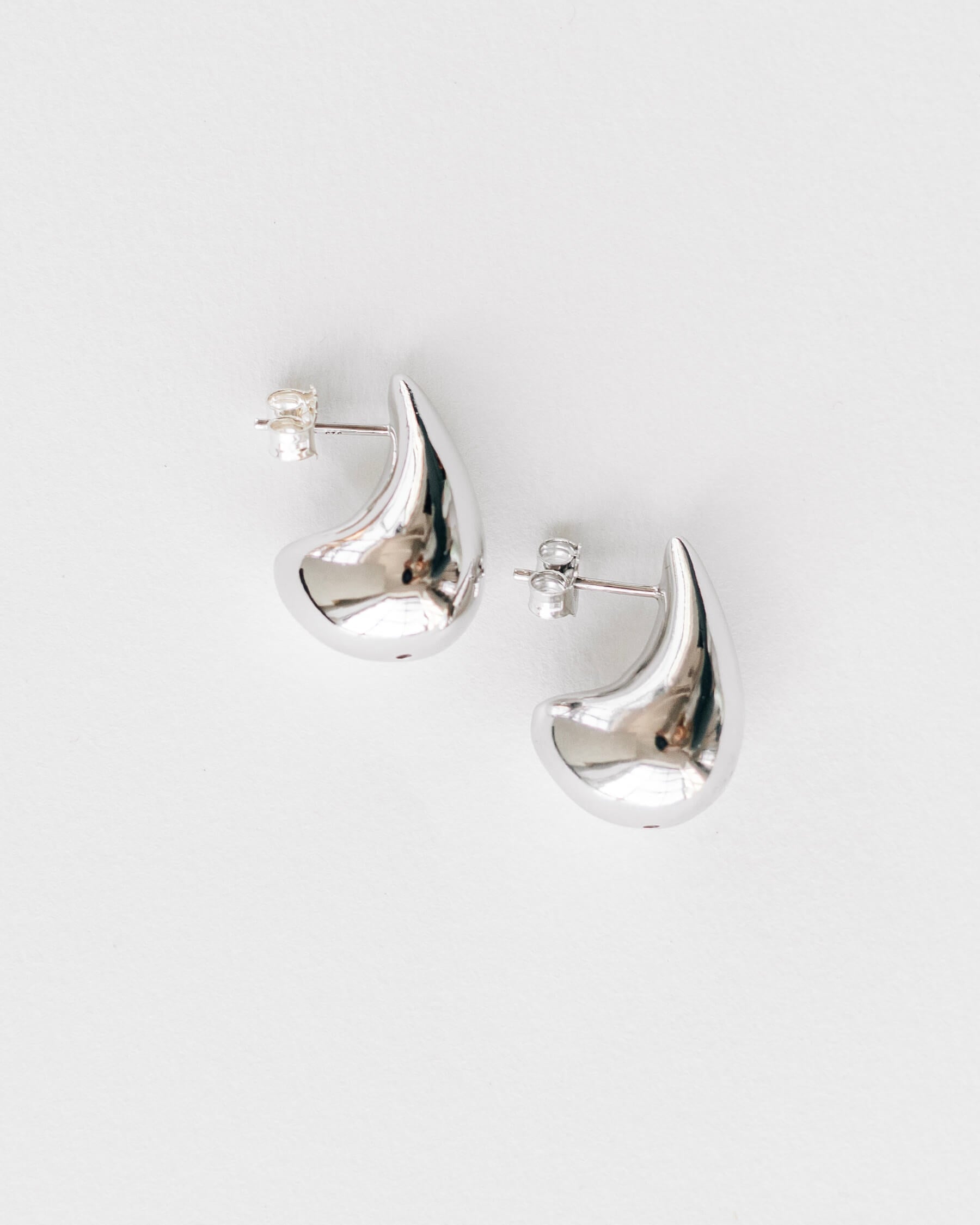 Stora droppformade örhängen i rhodiumpläterat 925 sterling silver, visas från sidan.