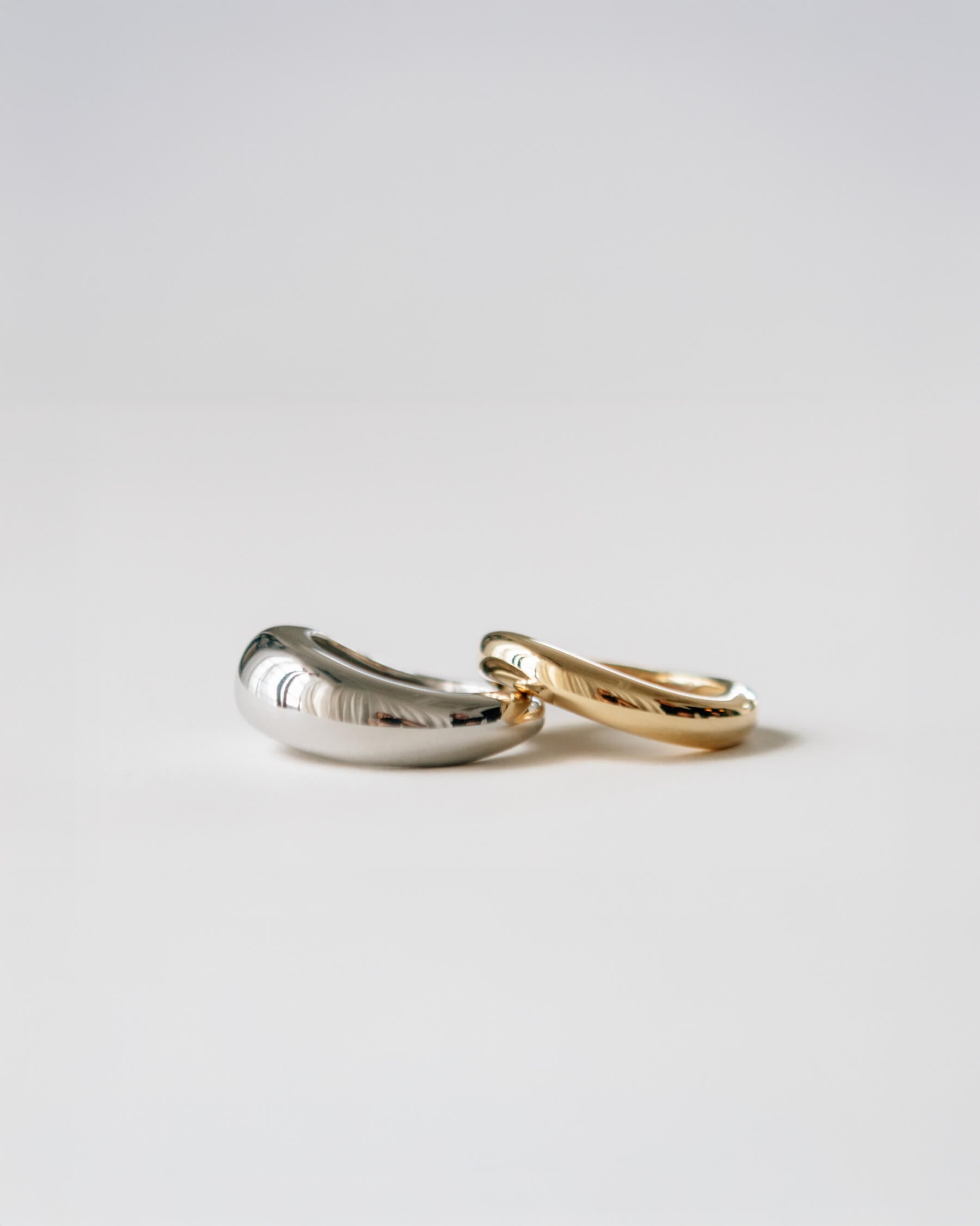 Två blanka ringar i olika bredd. Den bredare ringen i rhodiumpläterat 925 sterling silver och den tunnare i guldpläterat 925 sterling silver.