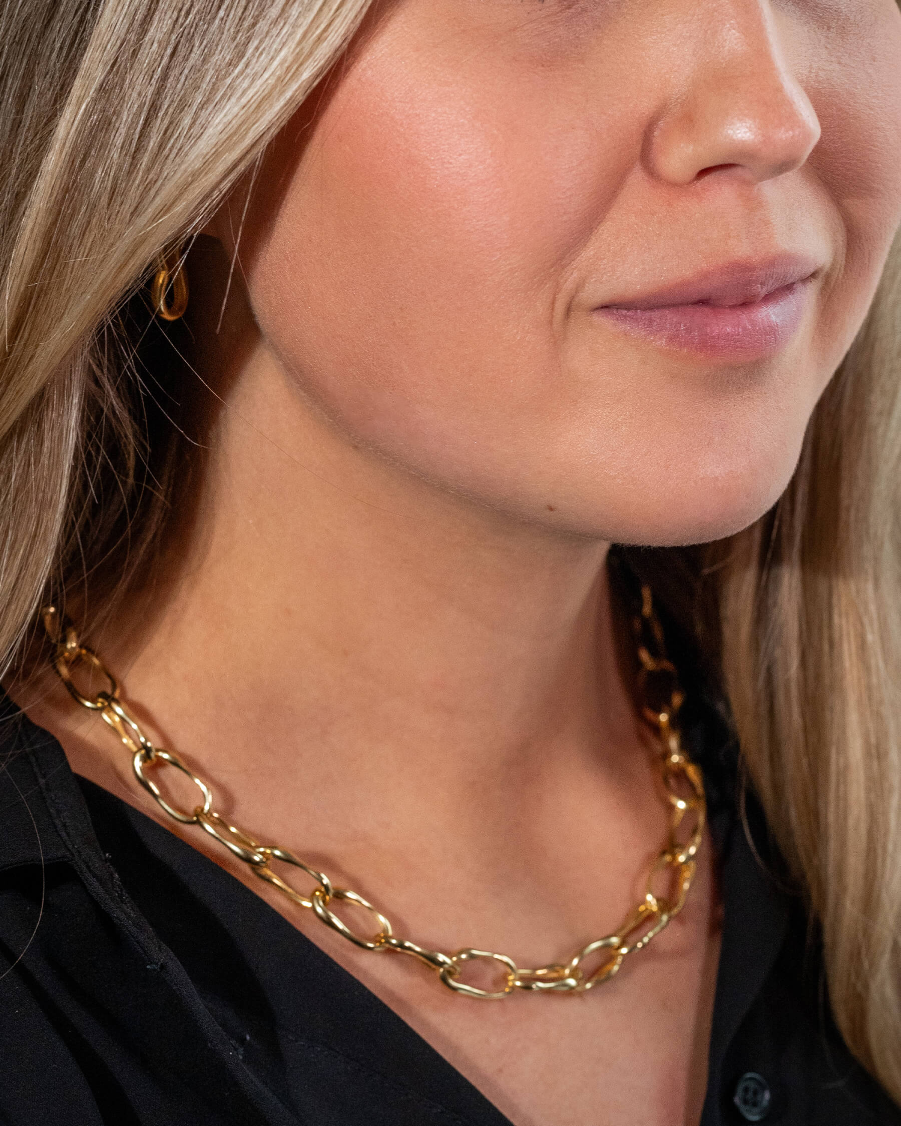 Kvinna med svart topp, hoops i guldpläterat sterling silver och halsband i guldpläterat sterling silver.
