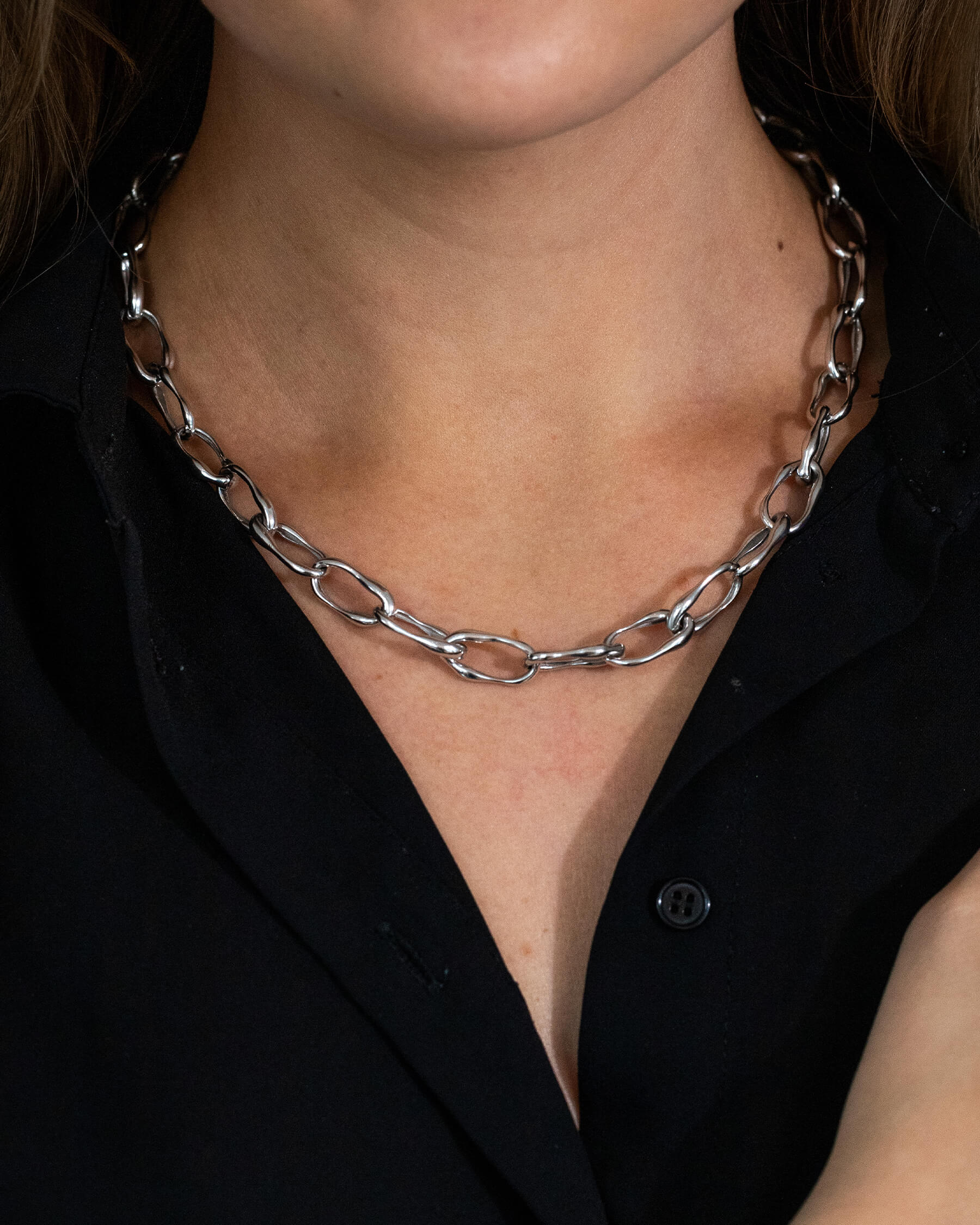 Kvinna i svart topp och halsband i sterling silver med länkar.