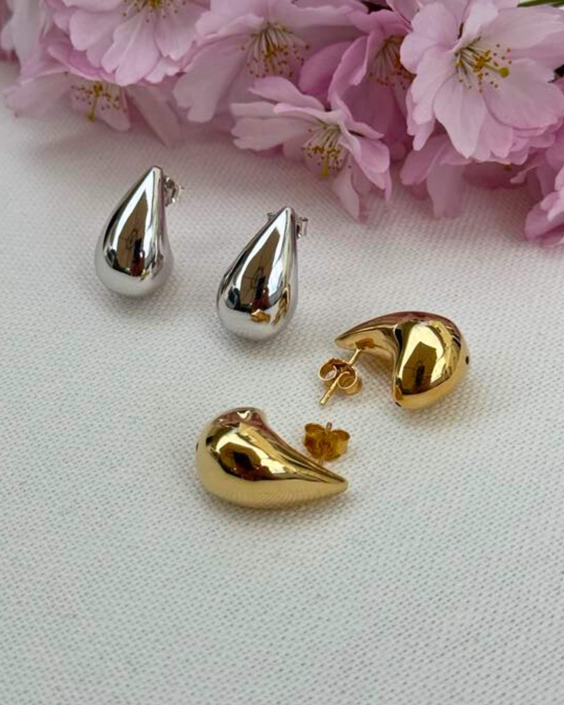 Två par droppformatde örhängen i rhodium (silver) - och guldpläterat 925 sterling silver samt rosa körsbärsblommor som dekoration.