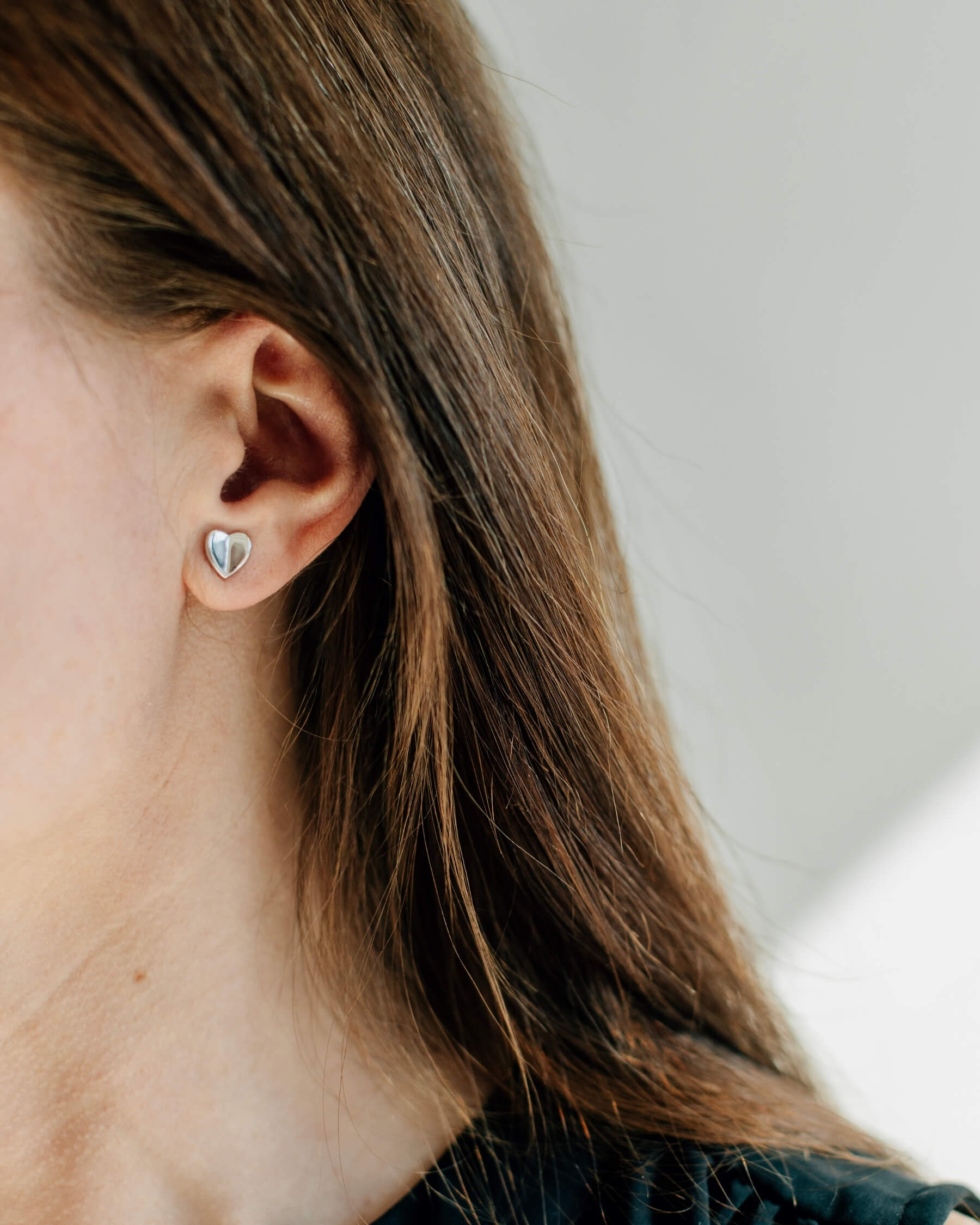 Närbild på ett öra som bär ett örhänge i form av ett hjärta, tillverkat i rhodiumpläterat 925 sterling silver.